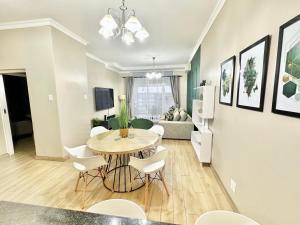 a dining room and living room with a table and chairs at Elegant Emerald King Size 2 Bed Apartment - Free Parking - Free Wifi in Durban