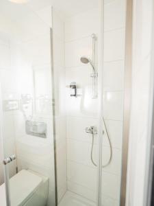 a white bathroom with a shower and a toilet at Fischerhof Glinzner Hotel-Restaurant-Camping in Afritz