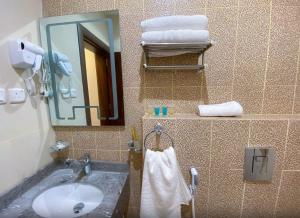a bathroom with a sink and a mirror and towels at نسناس للأجنحة الفندقية in Namirah