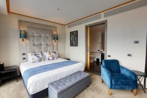 オークランドにあるMarsden Viaduct Hotelのベッドルーム(大型ベッド1台、青い椅子付)