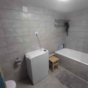 ein Badezimmer mit einer Badewanne und einem weißen Kühlschrank in der Unterkunft Old Buda Family Home in Budapest