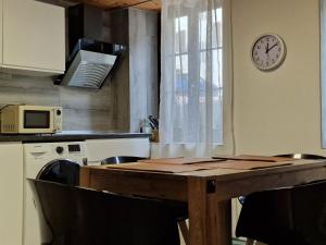 a kitchen with a table and a clock on the wall at Babylone in Orvin