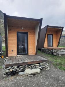 eine Blockhütte mit einer Terrasse und einem Gebäude in der Unterkunft Tiny House Kazbegi in Kazbegi