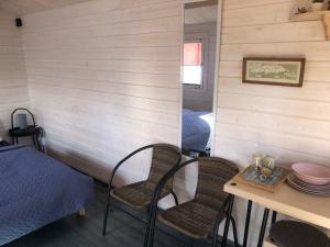 Zimmer mit 2 Stühlen, einem Tisch und einem Bett in der Unterkunft WOMOCAMP Holzhütte 2 in Saulkrasti