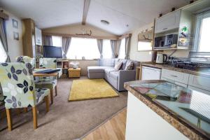 a kitchen and living room with a couch and a table at Lovely 6 Berth Caravan With Decking To The Side In Heacham Ref 21009i in Heacham