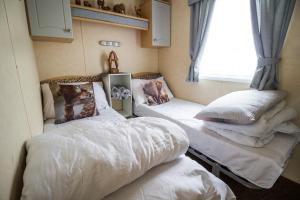 two beds in a room with a window at Lovely 6 Berth Caravan With Decking To The Side In Heacham Ref 21009i in Heacham