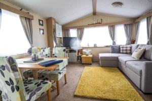 a living room with a couch and a table at Lovely 6 Berth Caravan With Decking To The Side In Heacham Ref 21009i in Heacham