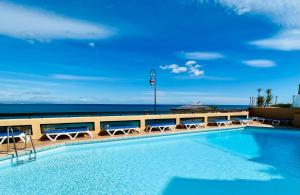 a swimming pool with chairs and the ocean in the background at Vue exceptionnelle sur la baie de Collioure in Collioure