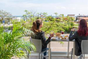 dos mujeres sentadas en una mesa con comida y bebidas en Hotel Atlas, en Cesenatico