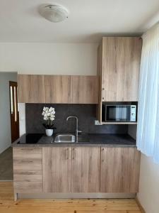a kitchen with wooden cabinets and a sink and a microwave at Bungalows SPORT CENTAR in Međugorje