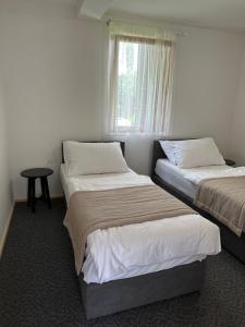 two beds in a room with a window at Bungalows SPORT CENTAR in Međugorje +19 photos