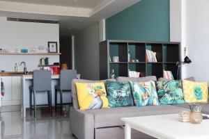 a living room with a gray couch with colorful pillows at The Bay Condominium, 1-bed apartment with stunning sea views in Koh Samui