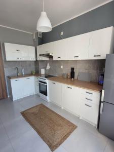 a kitchen with white cabinets and a brown rug at Apartament Słowińców 32 in Wejherowo