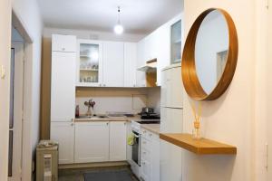 eine Küche mit weißen Schränken und einem runden Spiegel in der Unterkunft Útulný byt blízko centra in Koliba