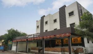 ein weißes Gebäude mit einem Schild auf der Vorderseite in der Unterkunft Hotel Rajshree in Ahmednagar