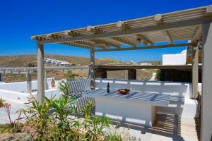 a patio with a table and a pergola at Miramare Suites Mykonos in Merchia Beach