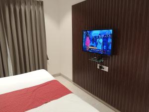 Schlafzimmer mit einem Bett und einem TV an einer Holztür in der Unterkunft Hotel Rajshree in Ahmednagar