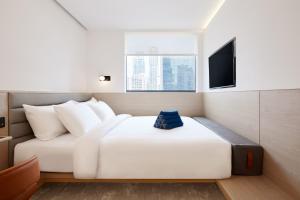 a bedroom with a white bed and a television at ASAI Bangkok Sathorn in Bangkok