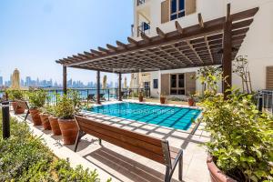 a swimming pool with a pergola and a bench at Modern 1 Bed Sea View Le Pont B1 La Mer in Dubai