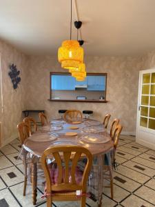 uma sala de jantar com uma mesa de madeira e cadeiras em Gîte aux portes des châteaux - 12 min de Beauval em Saint-Romain-sur-Cher