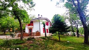 een klein wit huis met rode luiken in een tuin bij La Casa nel Bosco in Serino