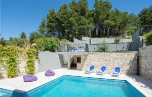 ein Pool mit zwei blauen Stühlen und ein Haus in der Unterkunft 5 Bedroom Amazing Home In Podstrana in Podstrana