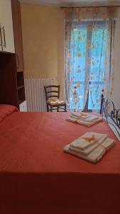 1 dormitorio con 1 cama roja y 2 toallas en Casa Vacanze “ Fonte del Borgo”, en Lanciano