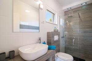 ein Bad mit einem Waschbecken, einem WC und einer Dusche in der Unterkunft Beachside Villa Marko in Milna