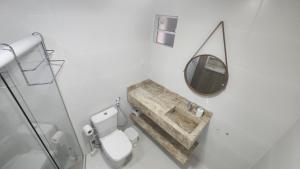 een witte badkamer met een spiegel en een toilet bij FLAT Jardim de Alah - Frente Praia in Salvador +34 foto's