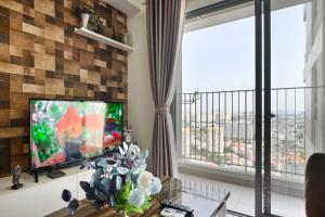 sala de estar con TV y ventanas grandes. en Landmark View 2 bedrooms condo in T1 Masteri Thao Dien, Fully Furnished With Full Amenities, en Ho Chi Minh