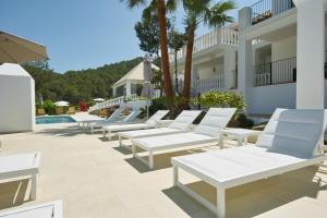 a row of white lounge chairs in front of a building at Hotel Rural Can Maries in Puerto de San Miguel