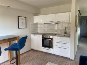 una cocina con armarios blancos y una silla azul en Stilvolles Apartment mit Sauna, en Burg
