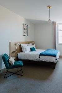 a bedroom with a large bed and a chair at Mage hôtels - Hôtel la grenette in Roanne