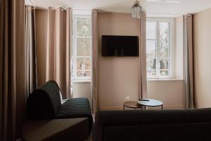 a living room with a couch and a tv at Mage hôtels - Hôtel la grenette in Roanne