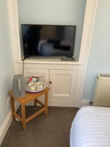 a room with a tv on a wall with a table at No 52 bed and breakfast in Helston