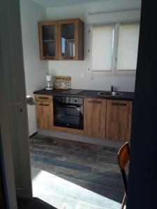 een keuken met houten kasten, een fornuis en een wastafel bij Maison du causse in Magalas