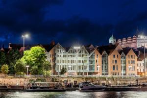 a large building next to a river at night at Space Apartments Old Town - River View in Szczecin