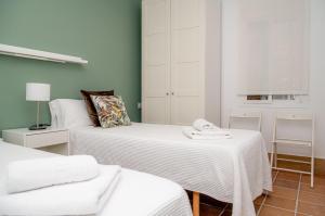 1 dormitorio con 2 camas con sábanas blancas en Apartamentos Casa Tuli A, ALJARAQUE, en Aljaraque