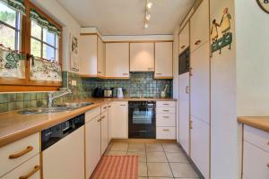 a kitchen with white cabinets and a sink at Quadze, Overlooking Village, Terrace & Bbq in Champéry
