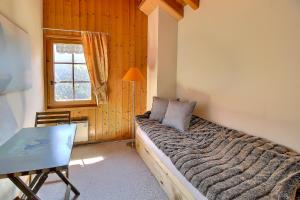 1 dormitorio con cama, mesa y ventana en Triplex Overlooking The Village - Terrace & Bbq en Champéry