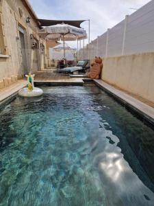 a swimming pool with an umbrella and some water at La Maison de Léonie sur Vias in Vias