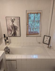 La salle de bains est pourvue d'une baignoire blanche et d'une fenêtre. dans l'établissement Maison Pimoli : Chambre Hortense, à Soustons