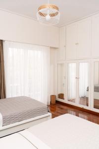 a white bedroom with two beds and a chandelier at Visum Acropol ,3BR - Private Terrace-Jacuzzi - Amazing View in Athens