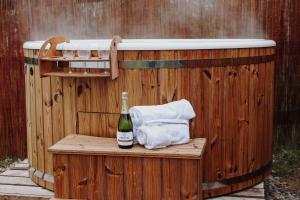 a hot tub with a bottle of champagne and towels at Biała Czapla Glamping z balią nad jeziorem czorsztyńskim in Maniowy