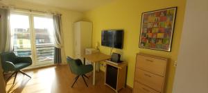 Habitación con escritorio, TV y sillas. en Zimmer mit Gartenblick, en Colonia