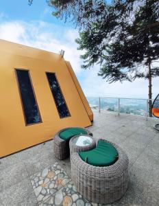 a yellow building with green chairs on a patio at De Pointé Resort & Resto in Campaka