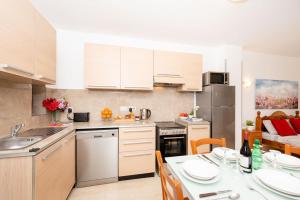 a kitchen with white cabinets and a table with a dining room at Sea Bliss Studio Apartment close to the sea - by Getawaysmalta in St. Paul's Bay