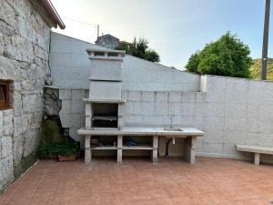 una pared de piedra con un banco frente a un fregadero en Villa Vaquiña, en Airoa