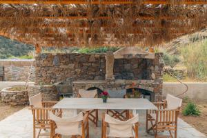 a table and chairs in front of a stone fireplace at Houses at Chrisopigi Sifnos in Chrisopigi
