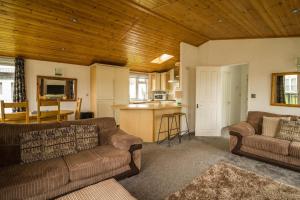 sala de estar con 2 sofás y cocina en Modern 4 Berth Lodge With Decking At Manor Park In Hunstanton Ref 23024w, en Hunstanton